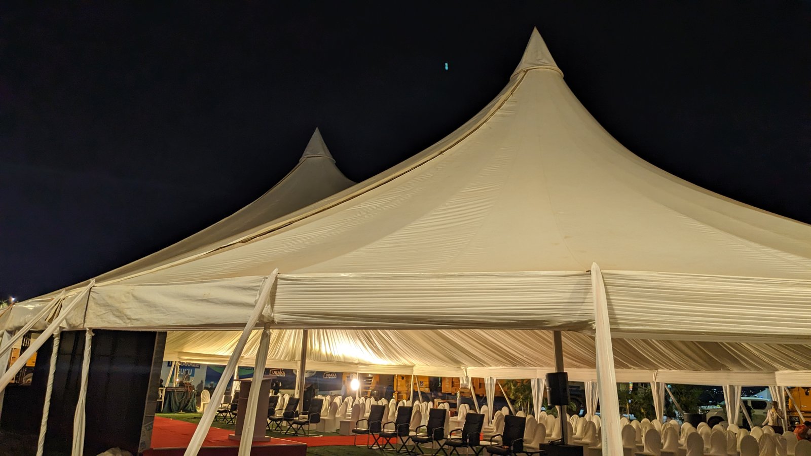 Double-peak marquee tent illuminated at night for corporate event in Kigali